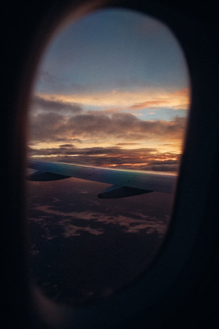 A scenic view of an airplane wing against a vibrant sunset sky, captured from a plane window.