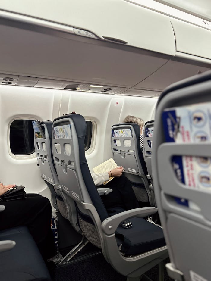 A passenger comfortably reading a book while flying on a commercial airplane.