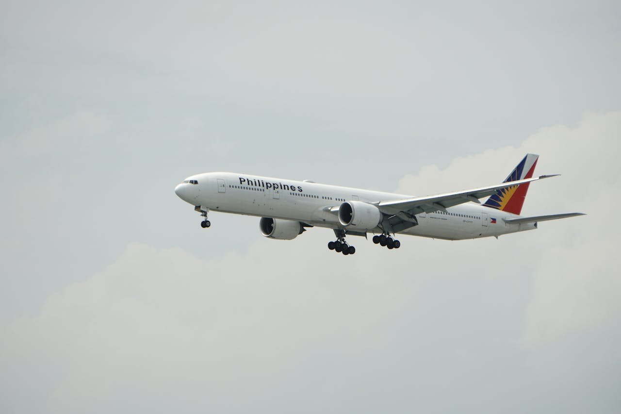 A Philippine Airlines Boeing 777 aircraft flying against a cloudy sky.