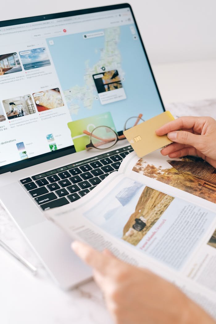 The Art of Drawing Readers In: Your attractive post title goes here Hands holding credit card over laptop and magazine for online shopping and travel planning.